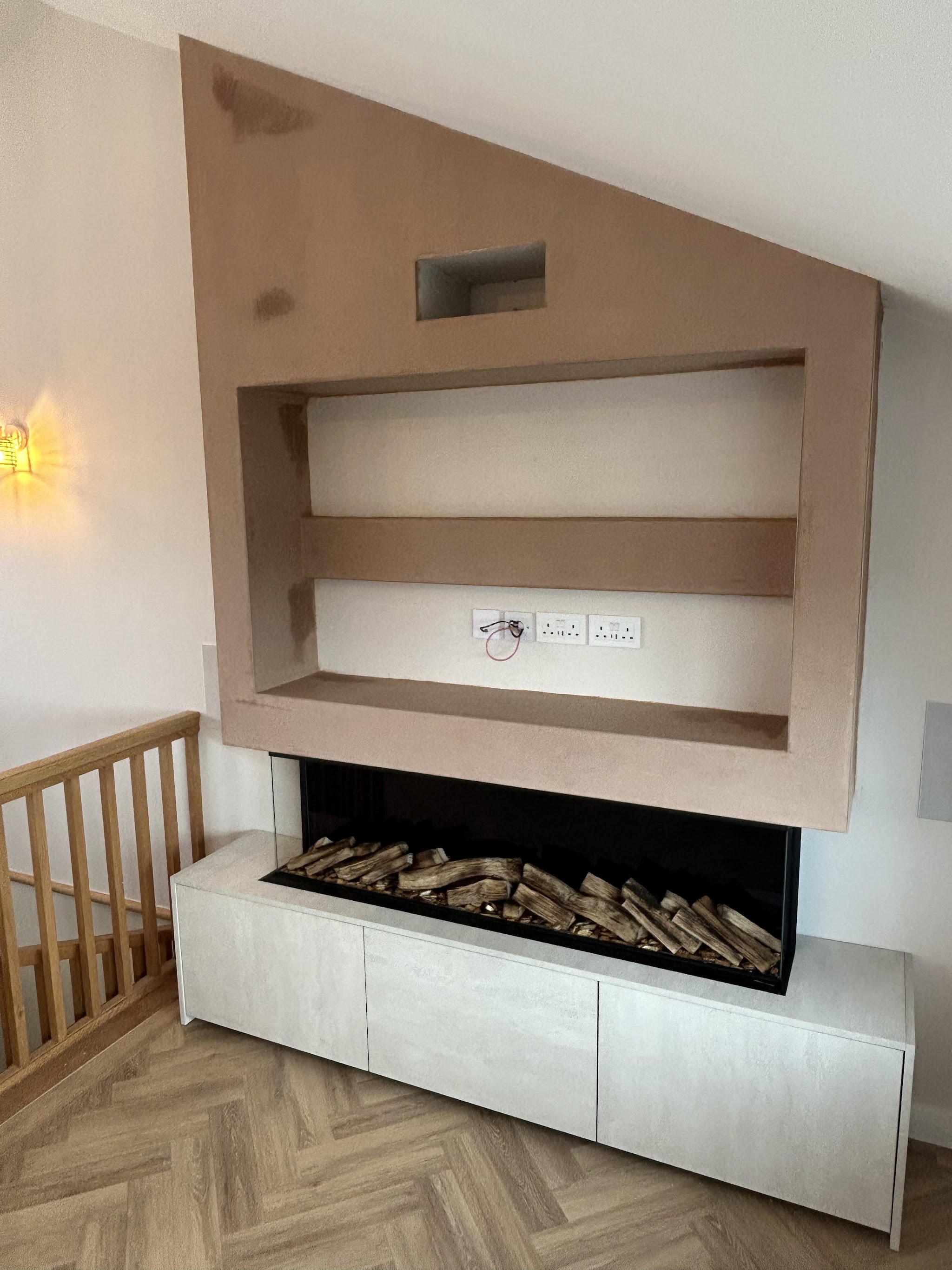 Fresh plaster surrounding a media wall and fireplace, before decoration
