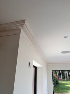 White interior with decorative coving along the ceiling and an open doorway